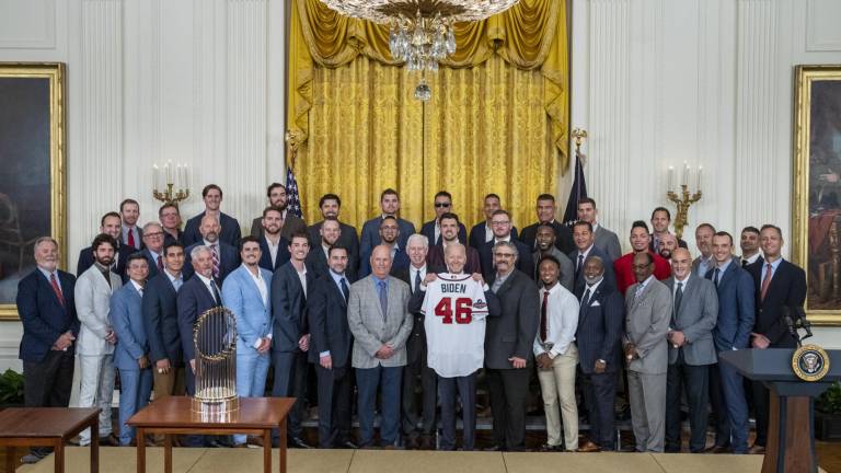 Joe Biden muestra el jersey con su apellido, junto a peloteros, entrenadores y directivos de los Bravos de Atlanta.