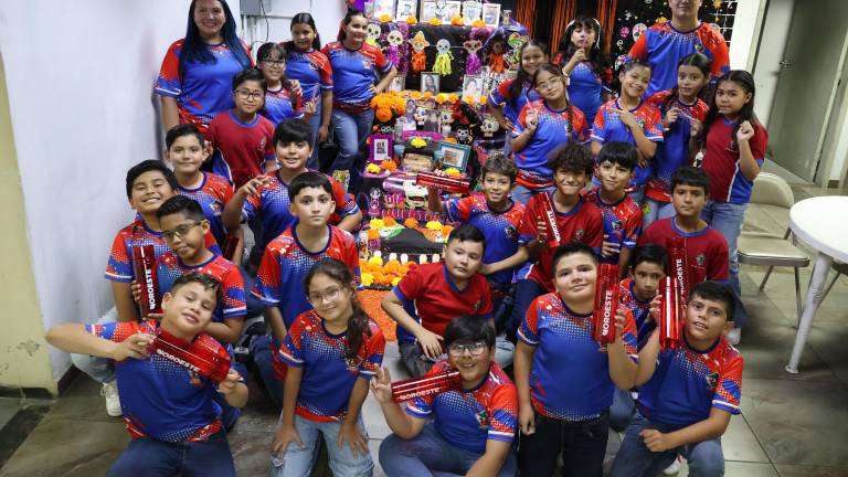 Los pequeños estudiantes de la Escuela Primaria Justo Sierra junto a su maestra Hilda Fabiola Osuna y el auxiliar Víctor, se toman la fotografía del recuerdo en el altar de Día de Muertos de Noroeste.