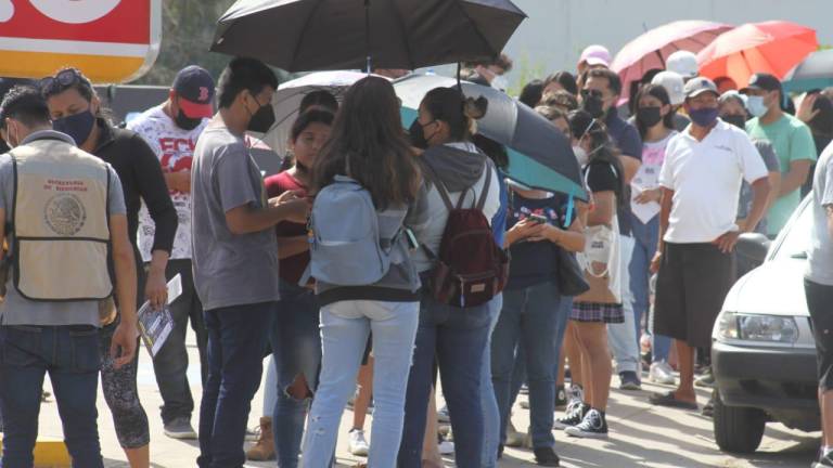 Larga fila de adolescentes con sus padres se hace durante la jornada de vacunación en Mazatlán.