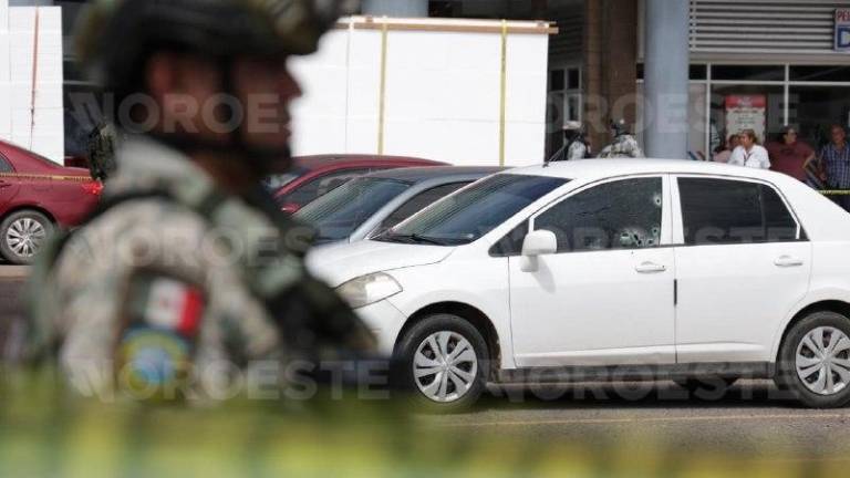 Autoridades resguardan el área del estacionamiento donde fue asesinado un hombre al interior de su vehículo.