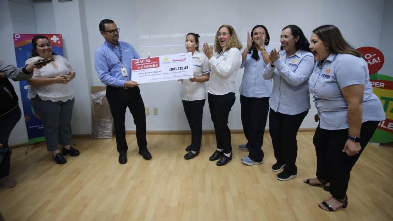 Personal de la asociación civil Formación y Desarrollo de la Niñez reciben el donativo de 300 mil pesos captado con la campaña de redondeo en una cadena de farmacias.