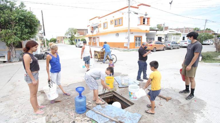 Vecinos de diferentes colonias abren los registros donde pasan los cables de Teléfonos de México para sacar el vital líquido acumulado con la lluvia.