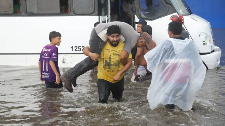 Voluntarios ayudaron a los pasajeros a bajar del camión urbano, ante la fuerte inundación registrada en la Avenida Internacional, a la altura de Lomas de Juárez.