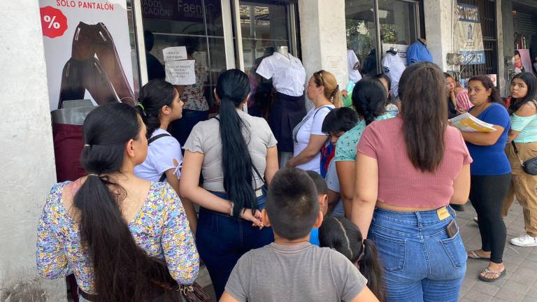 Padres de familia siguen acudiendo a los centros de canje en Culiacán a recoger los uniformes escolares, aunque comerciantes reportan aún baja demanda.