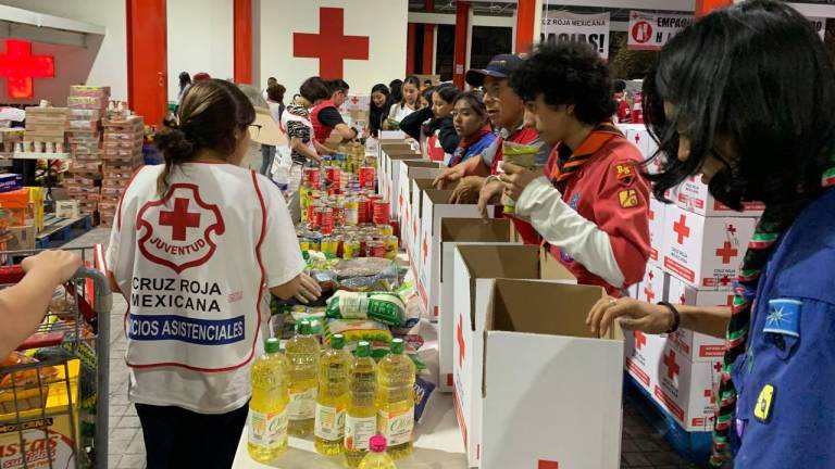 Un grupo de jovenes exploradores, participa en el empaquetado de alimentos en el centro de acopio de la Cruz Roja.