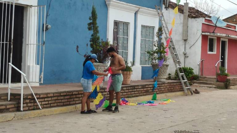 Vecinos colocan banderines de distintos colores.