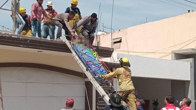 Personal de bomberos atiende a un trabajador que sufrió una descarga eléctrica.