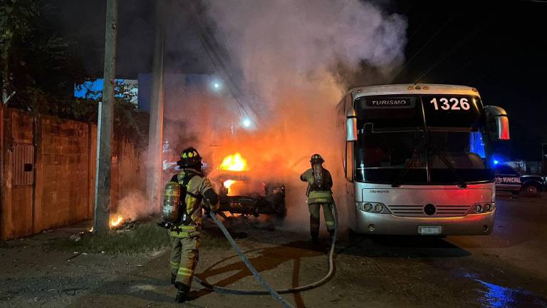 Elementos de bomberos sofocan el fuego de una camioneta incendiada.