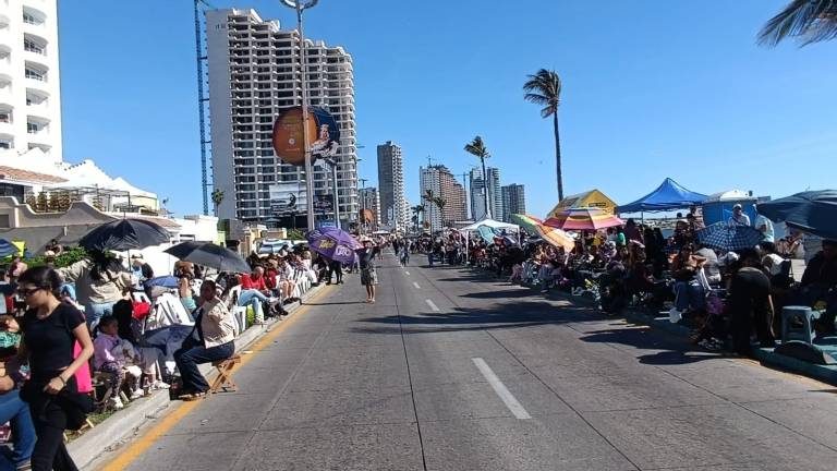 Familias, turistas nacionales y extranjeros esperan bajo el intenso sol el paso de 30 carros alegóricos y el cortejo real.