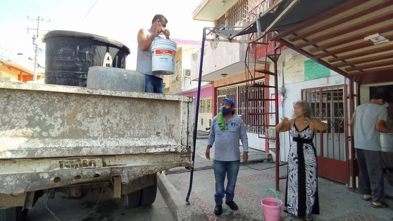 Reparte personal de Jumapam agua por la calle Juan Escutia, de la Colonia Benito Juárez.