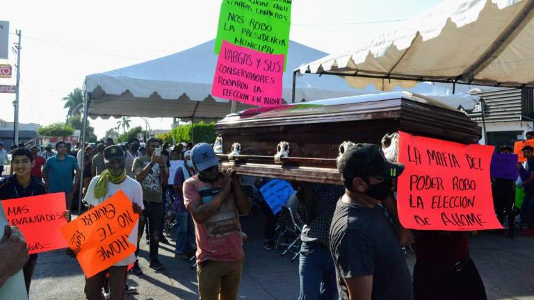 “La mafia del poder se robó la elección de Ahome”, dice una cartulina frente al ataúd de madera.