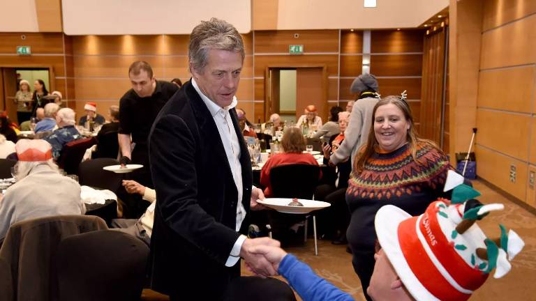 Hugh Grant sirve comida a personas mayores de bajos recursos en Londres.