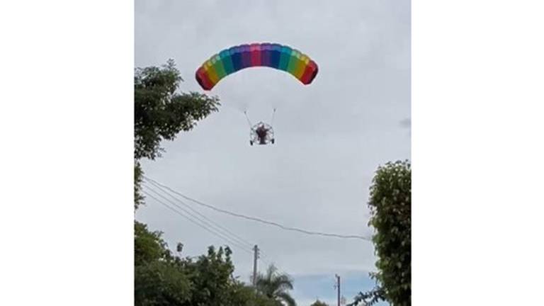 Desde un parapente, el canadiense Joe Irvin regala dulces a niños de Teacapán desde un parapente.