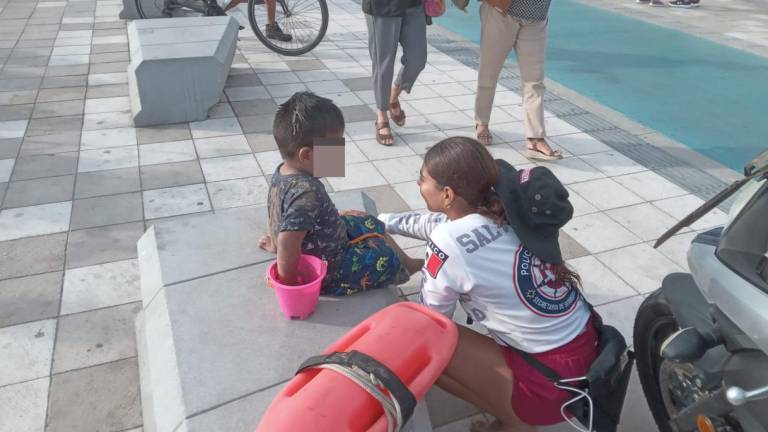 Uno de los menores extraviados es atendido por una joven salvavidas de Mazatlán.