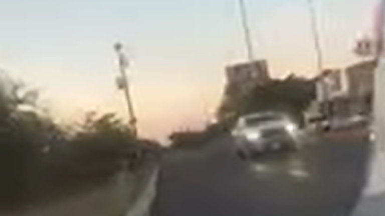 Momento en que una camioneta blanca pasa a toda velocidad y sus ocupantes disparan contra elementos de la Guardia Nacional. Esta imagen es captura del video de Luz Noticias.