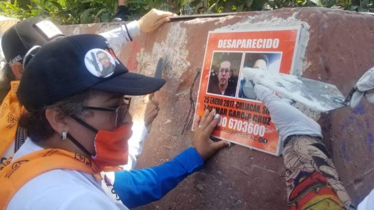 Isabel Cruz Bernal pega una imagen de su hijo desaparecido en el primer cuadro de la ciudad de Culiacán para visibilizarlo