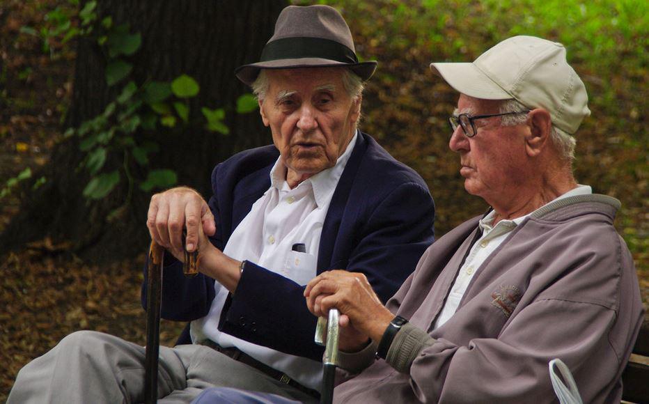 $!Dos hombres mayores conversan en el banco de un parque.