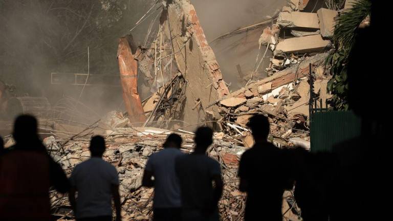 Los equipos de rescate observan cómo se retiran los escombros de un edificio derrumbado en Caracas, Venezuela.