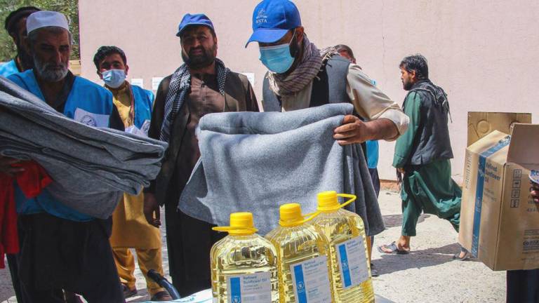 Personal humanitario de la ONU entrega alimentos y mantas a la gente necesitada en Kabul, Afganistán.