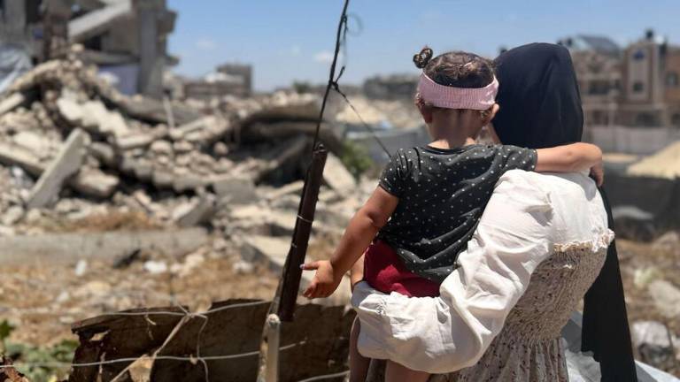 Una mujer palestina sostiene a una niña pequeña mientras contempla los escombros en Gaza.
