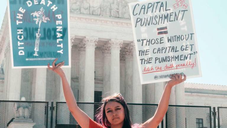 Un activista sostiene carteles contra la pena de muerte ante el edificio del Tribunal Supremo de EE.UU. en Washington, D.C. En una de las pancartas se lee: Pena capital: Los que no tienen capital son los únicos penados.