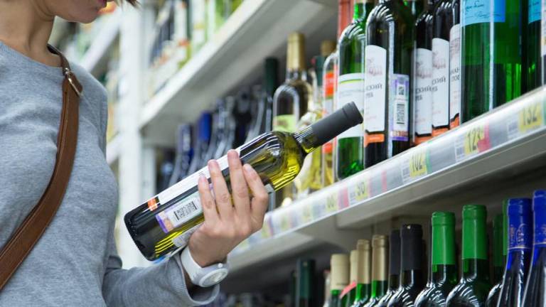 Una mujer observa una botella de vino en un supermercado de Moscú.