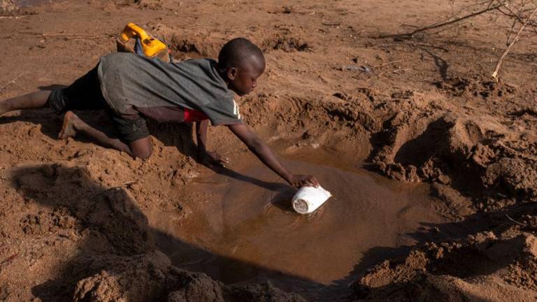 Un niño busca agua en los depósitos que quedan de un río seco en Somalia.