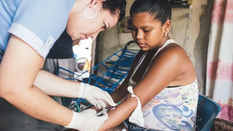 Un trabajador sanitario toma muestras de sangre a una mujer que había estado previamente enferma de dengue.