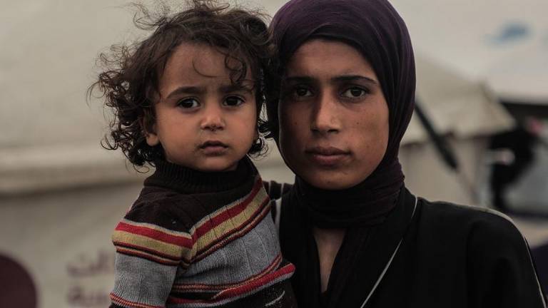 Una mujer palestina y su hijo frente a la tienda en la que viven en la ciudad de Gaza.