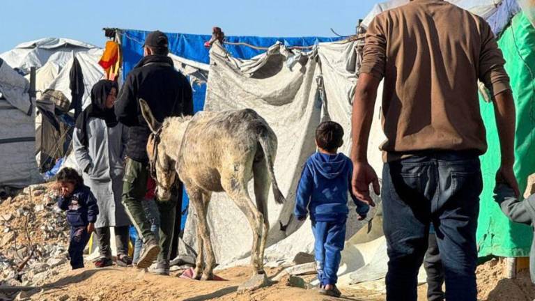 Los palestinos desplazados navegan a través de refugios improvisados a lo largo de la playa de Gaza.