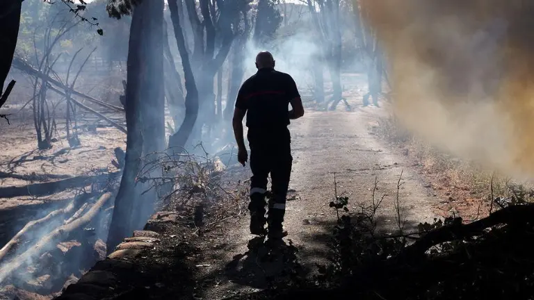 Un bombero inspecciona los restos humeantes de un incendio forestal en el sur de Francia.