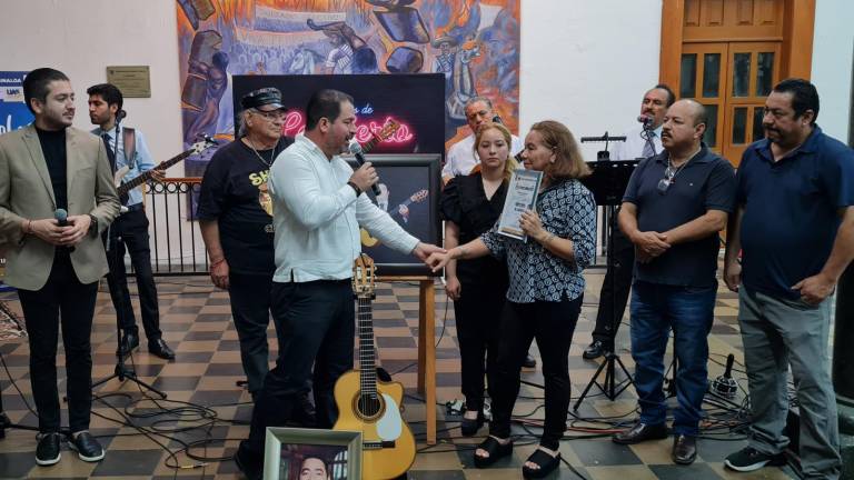 Miguel Ángel Espinoza Castillo hace entrega del reconocimiento a Judith Corrales, esposa del músico homenajeado Marco Aurelio Pérez.