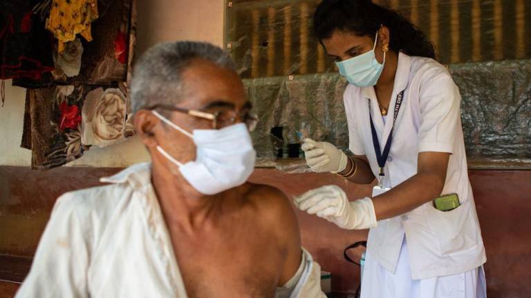 Un trabajador sanitario de la India vacuna a un adulto mayor contra el Covid-19.