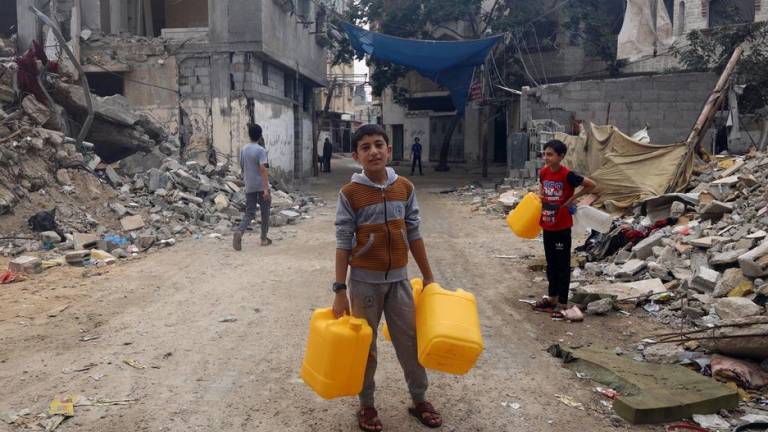 Niños buscando agua en un barrio bombardeado en Gaza.