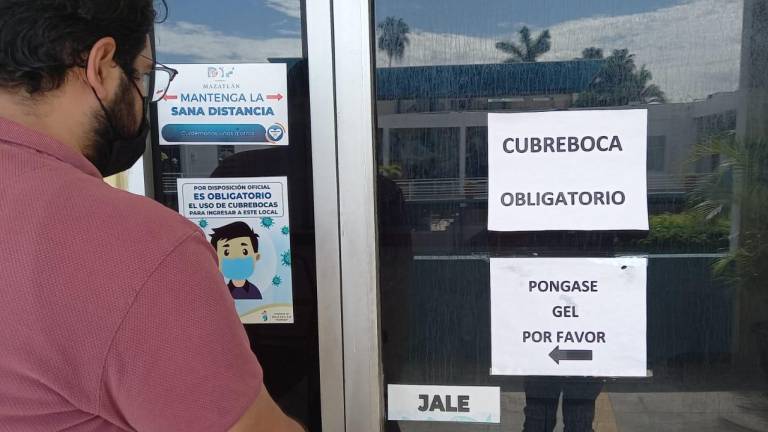 En las oficinas del Ayuntamiento de Mazatlán, colocan letreros para informar que ante la pandemia de Covid-19 atenderán por ventanilla o a una persona a la vez dentro de dependencias.