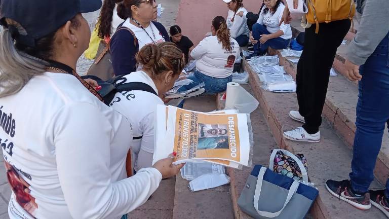 Integrantes del colectivo de búsqueda de Culiacán, Sabuesos Guerreras, pega fichas de búsqueda en el Centro de la ciudad.