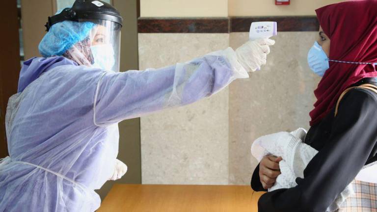 Toman la temperatura de una mujer en un centro de la Franja de Gaza durante la pandemia de Covid-19.