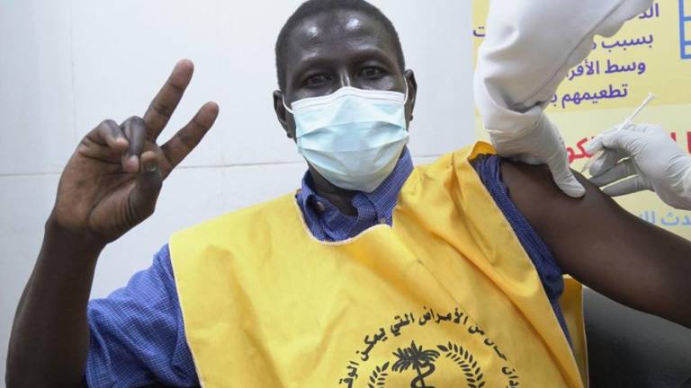 Un trabajador sanitario sudanés haciendo el signo de la victoria mientras se vacuna contra el Covid-19.